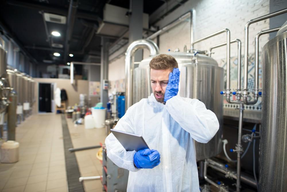Inspektor DDD łapiący się za głowe podczas sprawdzania obecnej dokumentacji HACCP w zakładzie produkcyjnym żywności
