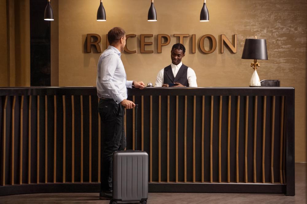 Recepcja hotelowa przyjmując jednego gościa z walizką