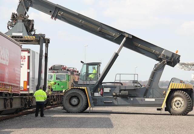Duża maszyna przeładunkowa podnosząca kontener z wagonu kolejowego